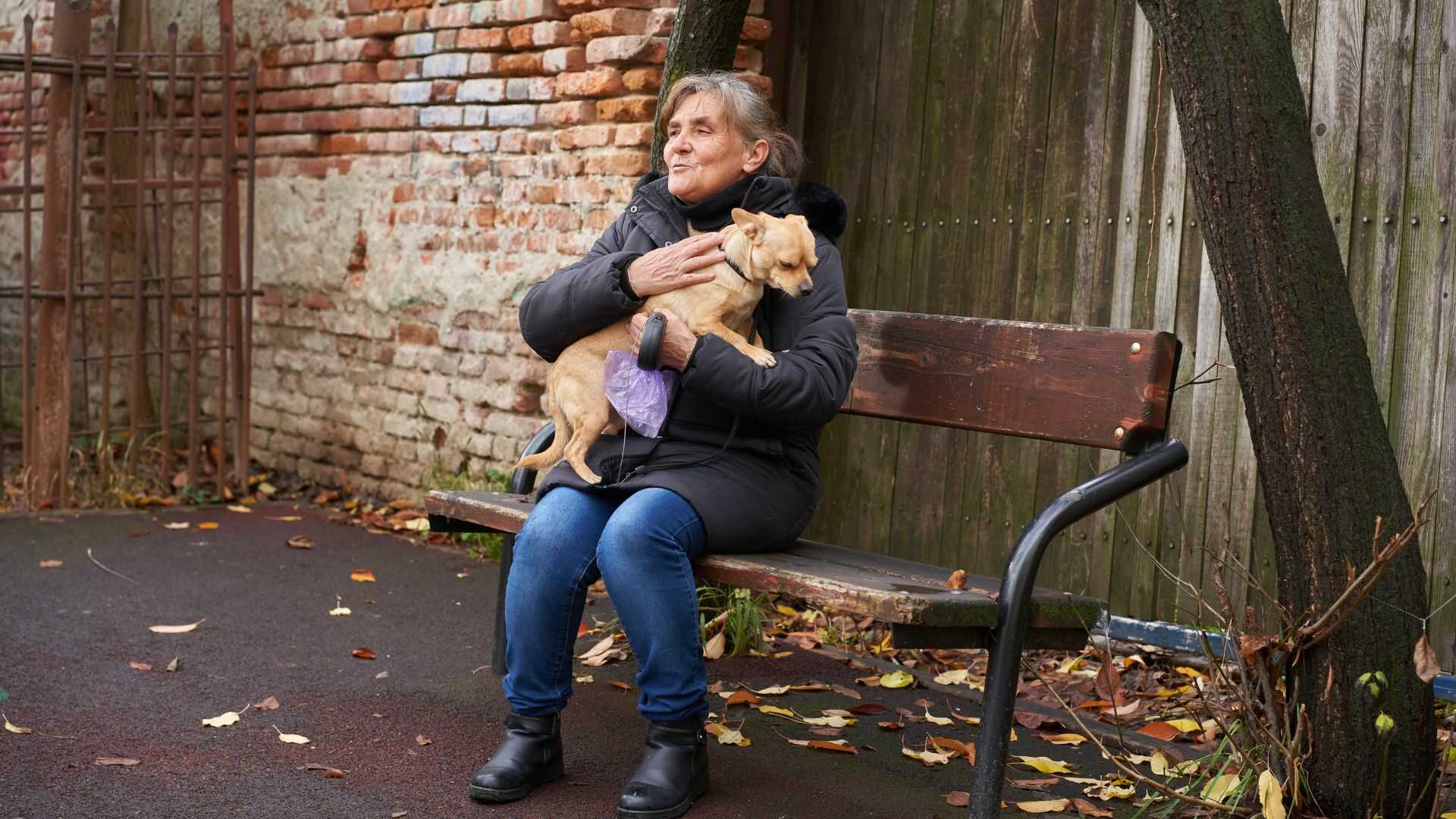 Starsza kobieta siedząca na kanapie z kotem na kolanach