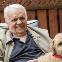 Starszy mężczyzna spacerujący z psem w parku