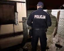 Policjant kontrolujący prowizoryczne miejsce schronienia podczas zimowego patrolu w Redzie