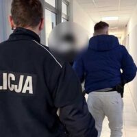 Policjanci prowadzą nieletnią osobę korytarzem budynku służbowego – zdjęcie ilustracyjne