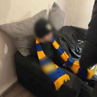 Zatrzymana osoba z klubowym szalikiem – elementy identyfikujące środowisko pseudokibiców (twarz zamazana)