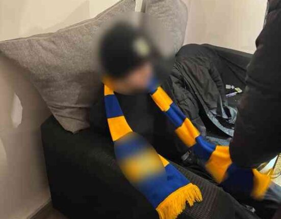 Zatrzymana osoba z klubowym szalikiem – elementy identyfikujące środowisko pseudokibiców (twarz zamazana)