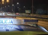 Policyjny radiowóz z włączoną belką świetlną „POLICJA” na tle nocnej drogi w okolicach Wejherowa