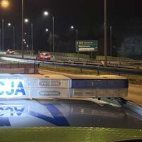 Policyjny radiowóz z włączoną belką świetlną „POLICJA” na tle nocnej drogi w okolicach Wejherowa