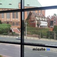 Widok Z Okna Na Gotycką Katedrę Oraz Dom Pokryty Bluszczem Przy Ruchliwej Ulicy.