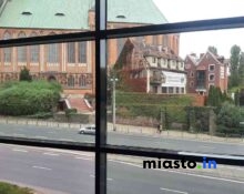 Widok Z Okna Na Gotycką Katedrę Oraz Dom Pokryty Bluszczem Przy Ruchliwej Ulicy.