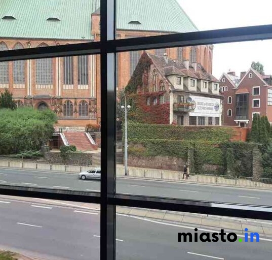 Widok Z Okna Na Gotycką Katedrę Oraz Dom Pokryty Bluszczem Przy Ruchliwej Ulicy.