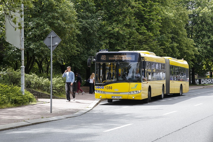 Żółty przegubowy autobus Solaris PKM Katowice numer 1350 na linii 48 w kierunku Skłodowskiej-Jodłowiec, jadący ulicą Katowic wśród zieleni drzew.
