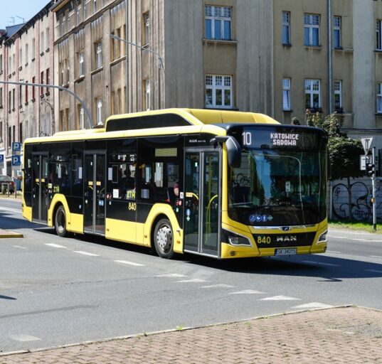Żółty autobus miejski MAN Lion's City numer 840 PKM Katowice na linii 10 w kierunku Sądowej, jadący przez skrzyżowanie w centrum Katowic.